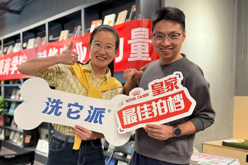 两人在交流活动中举着洗它派和皇家品牌手牌合影